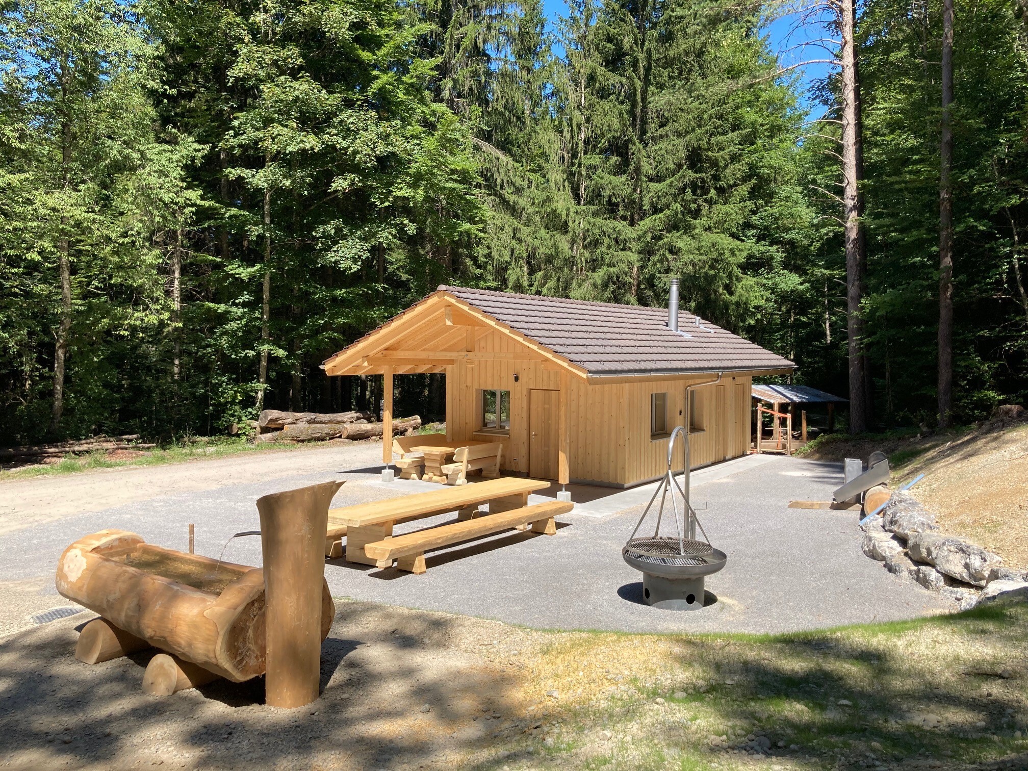 Waldhütte Hofholz von Aussen mit Brunnen, Feuerstelle und Sitzgelegenheit